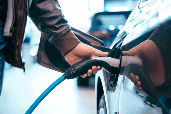 Una persona ricarica la sua auto ibrida o elettrica
