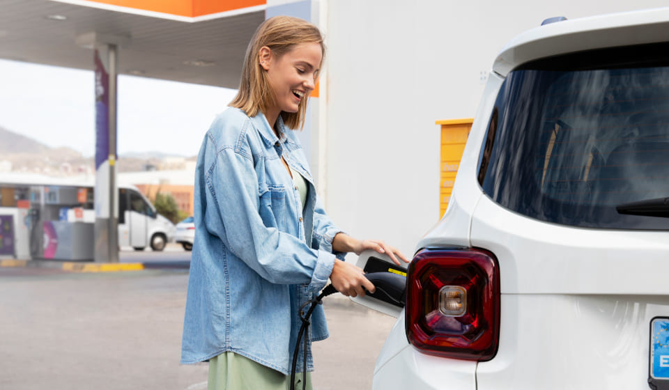 Quanto costa ricaricare un'auto elettrica in una stazione di servizio? Donna che ricarica l'auto elettrica in una stazione di servizio